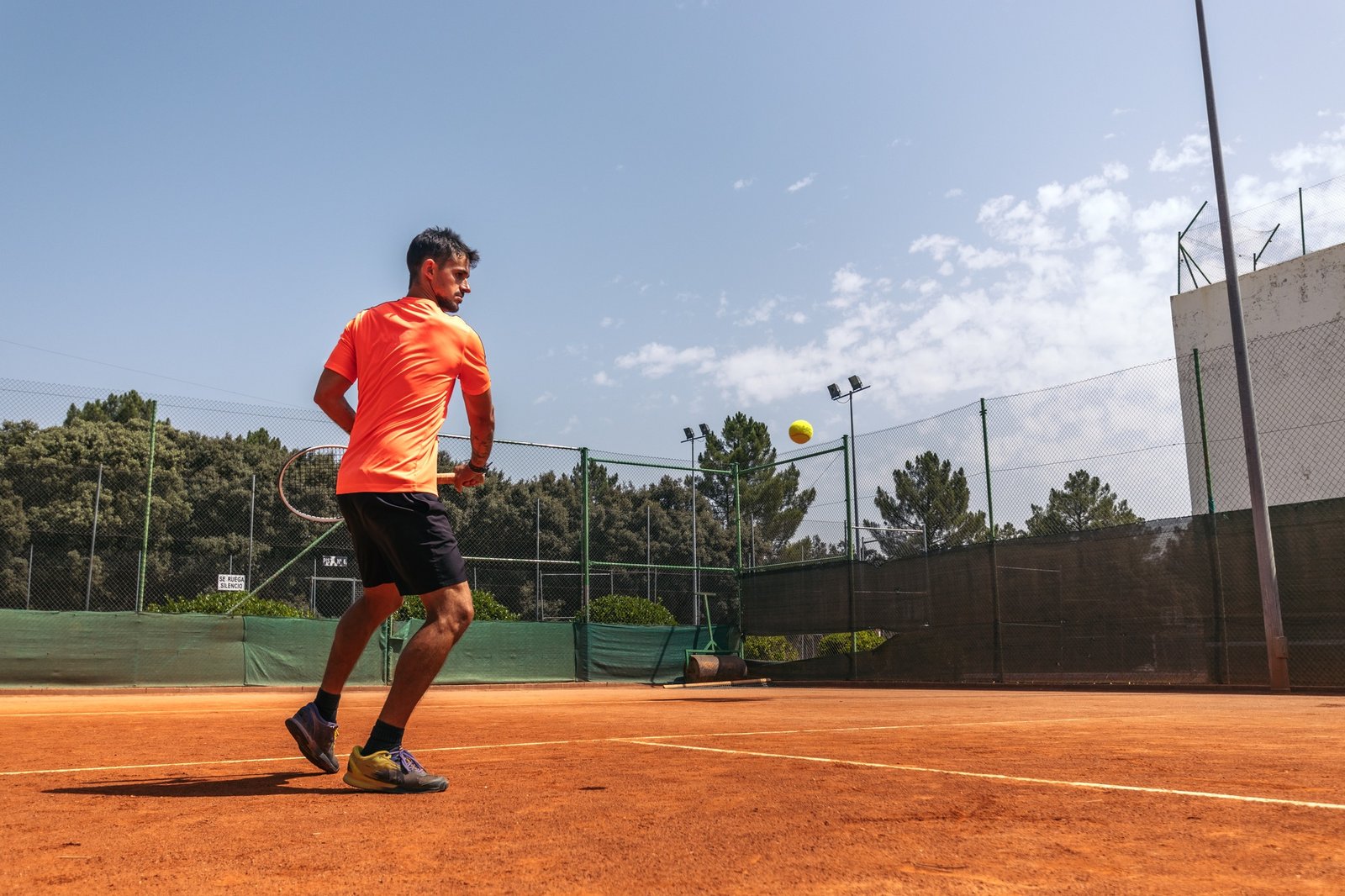 Man in sportswear playing tennis on a dirt tennis court